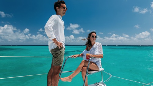 Un couple se détend sur un catamaran naviguant sur une mer turquoise